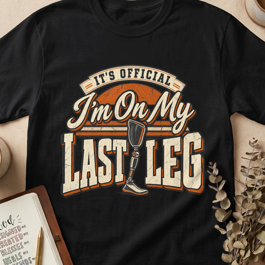 Black t-shirt with "It's Official I'm On My Last Leg" and prosthetic leg graphic.