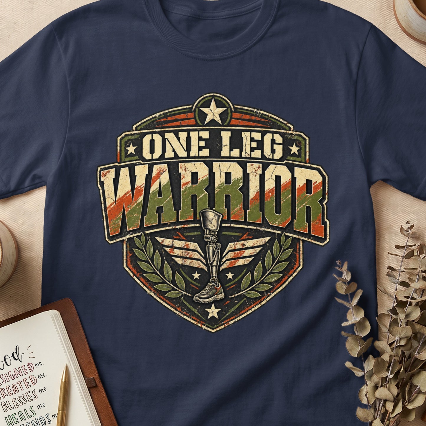 Navy t-shirt with "One Leg Warrior" emblem featuring a prosthetic leg and laurel wreath.