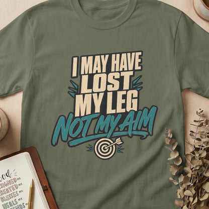 Olive green t-shirt with "I May Have Lost My Leg, Not My Aim" text and target graphic.
