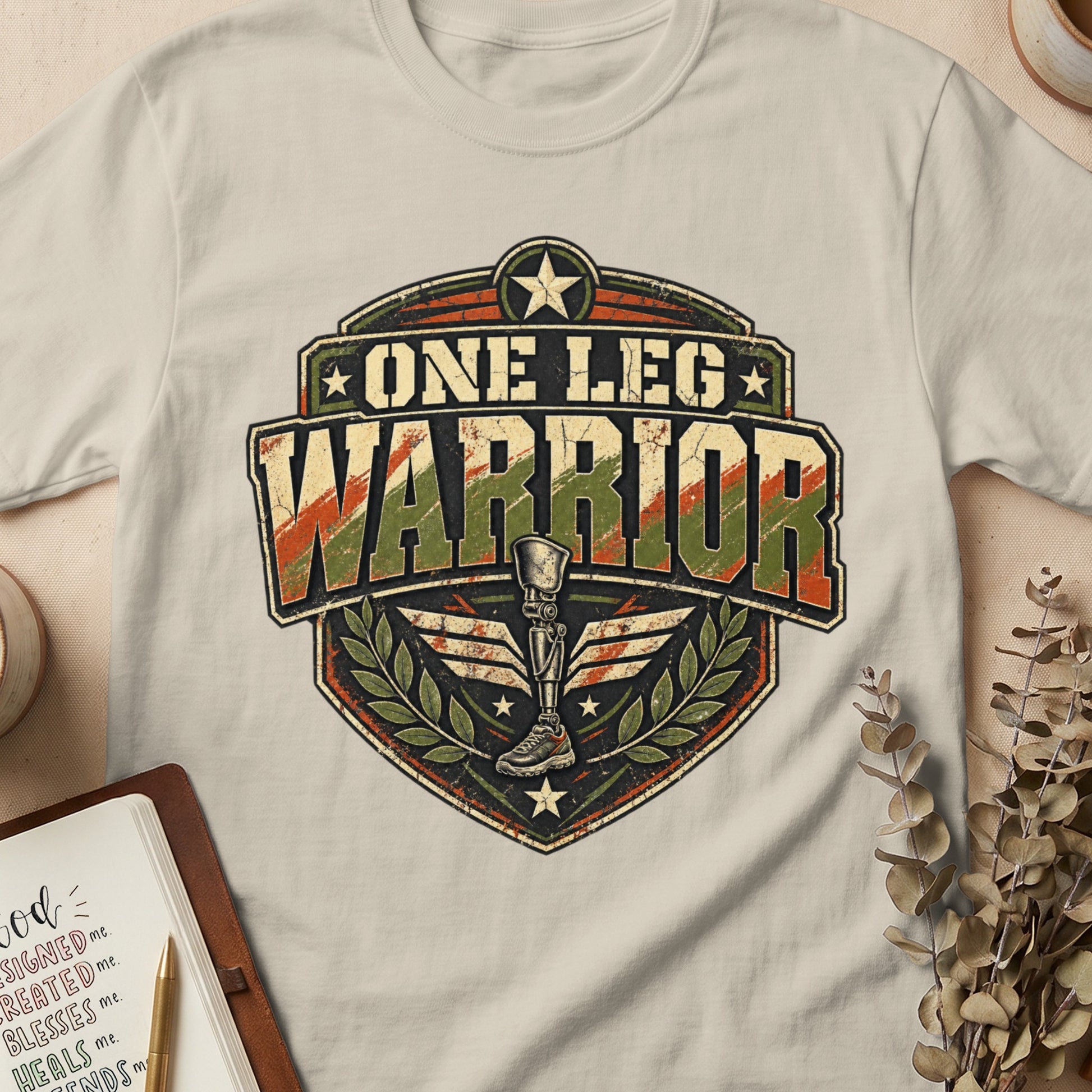 One Leg Warrior emblem with prosthetic leg and laurel wreath on a t-shirt.