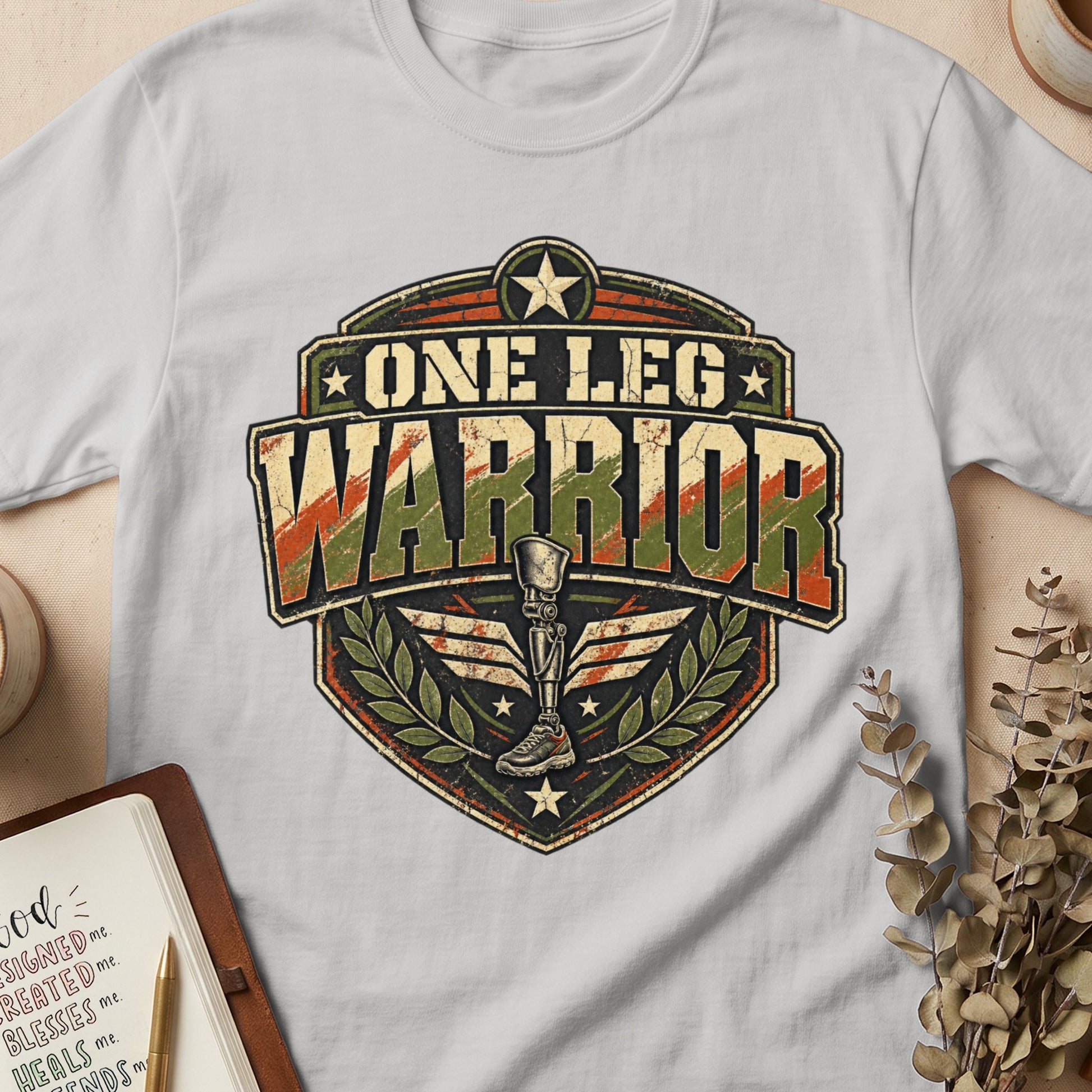"One Leg Warrior" emblem on a white t-shirt featuring a prosthetic leg.