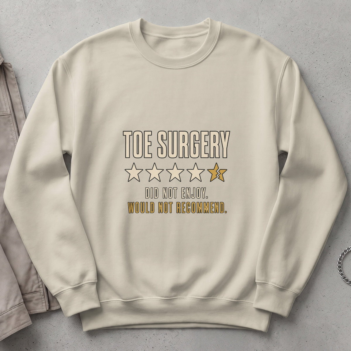 Cream sweatshirt with "Toe Surgery Did Not Enjoy. Would Not Recommend." text and broken star rating.