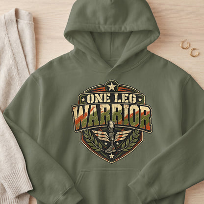 Olive green hoodie with "ONE LEG WARRIOR" graphic featuring a prosthetic leg and laurel wreath.