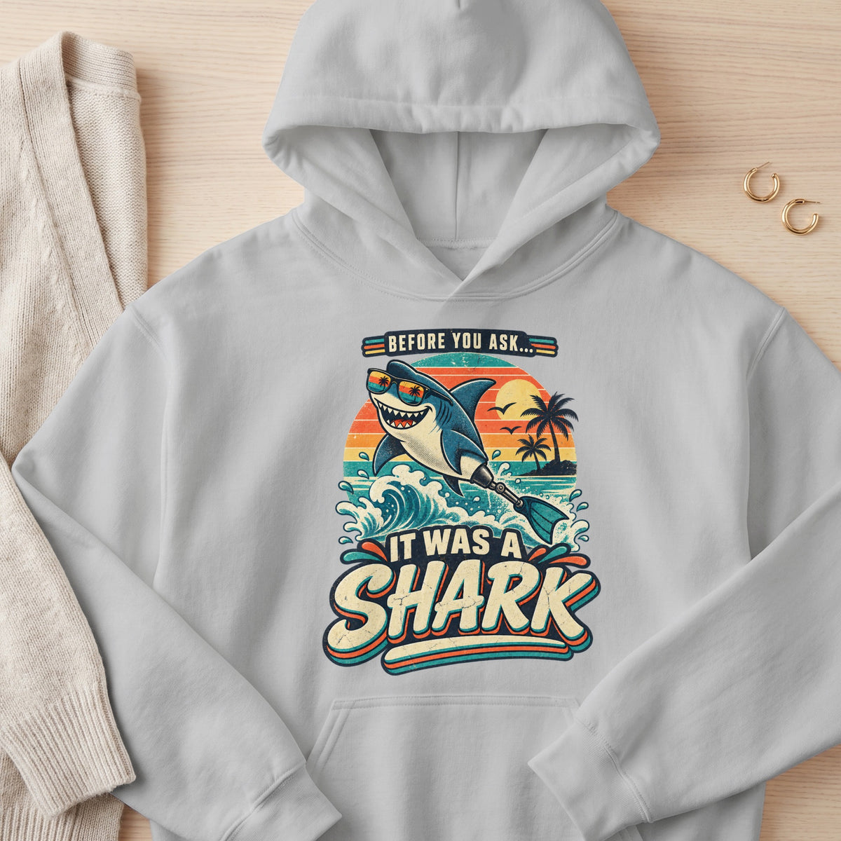 Gray hoodie with "Before You Ask... It Was A Shark" graphic featuring a shark with sunglasses and a flipper.