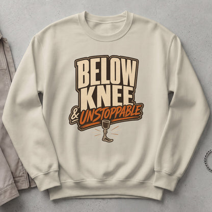 Cream sweatshirt with "Below Knee & Unstoppable" graphic and prosthetic leg.