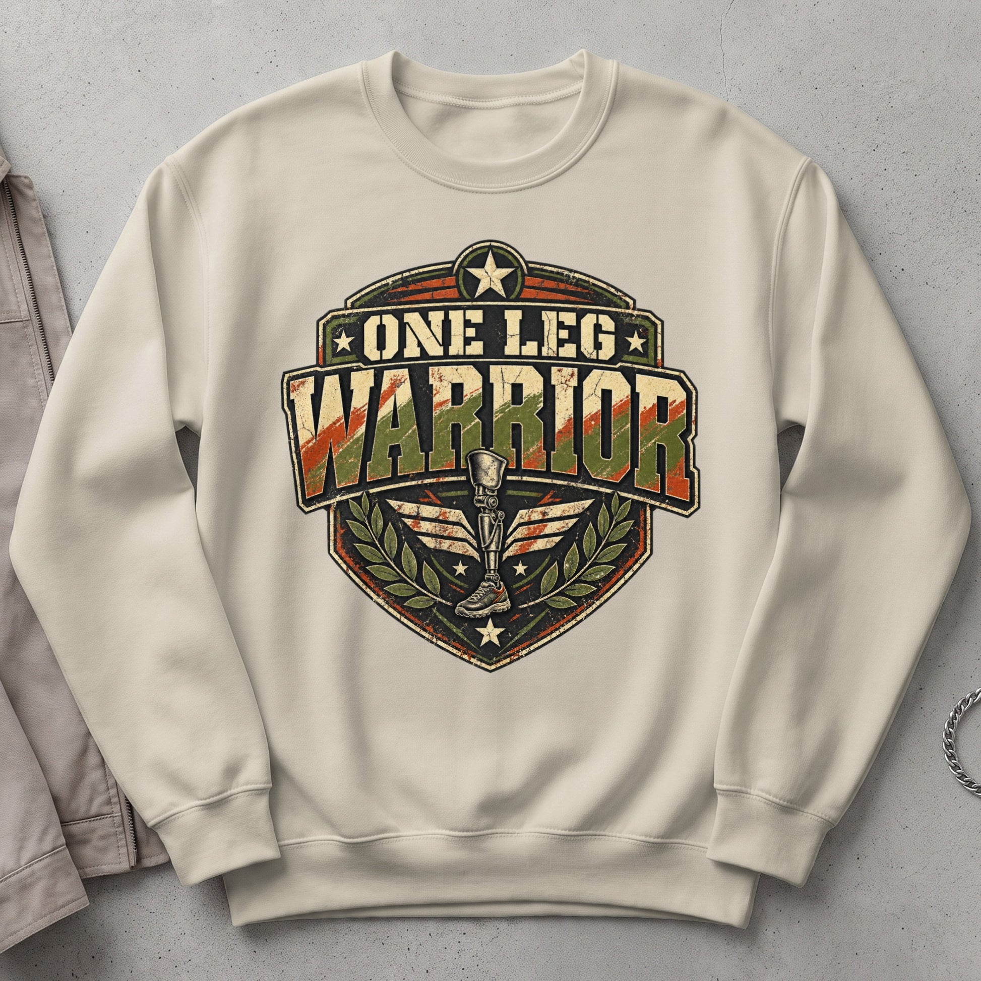Cream sweatshirt with "One Leg Warrior" crest featuring a prosthetic leg and wings.