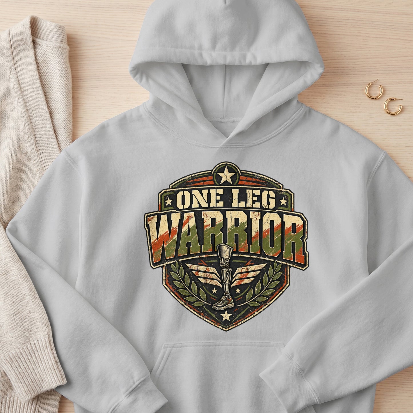 Light gray hoodie with "One Leg Warrior" distressed emblem featuring a prosthetic leg.