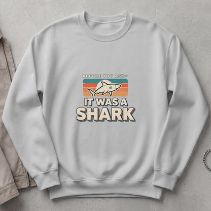White sweatshirt with "Before you ask... It was a shark" graphic and shark illustration.