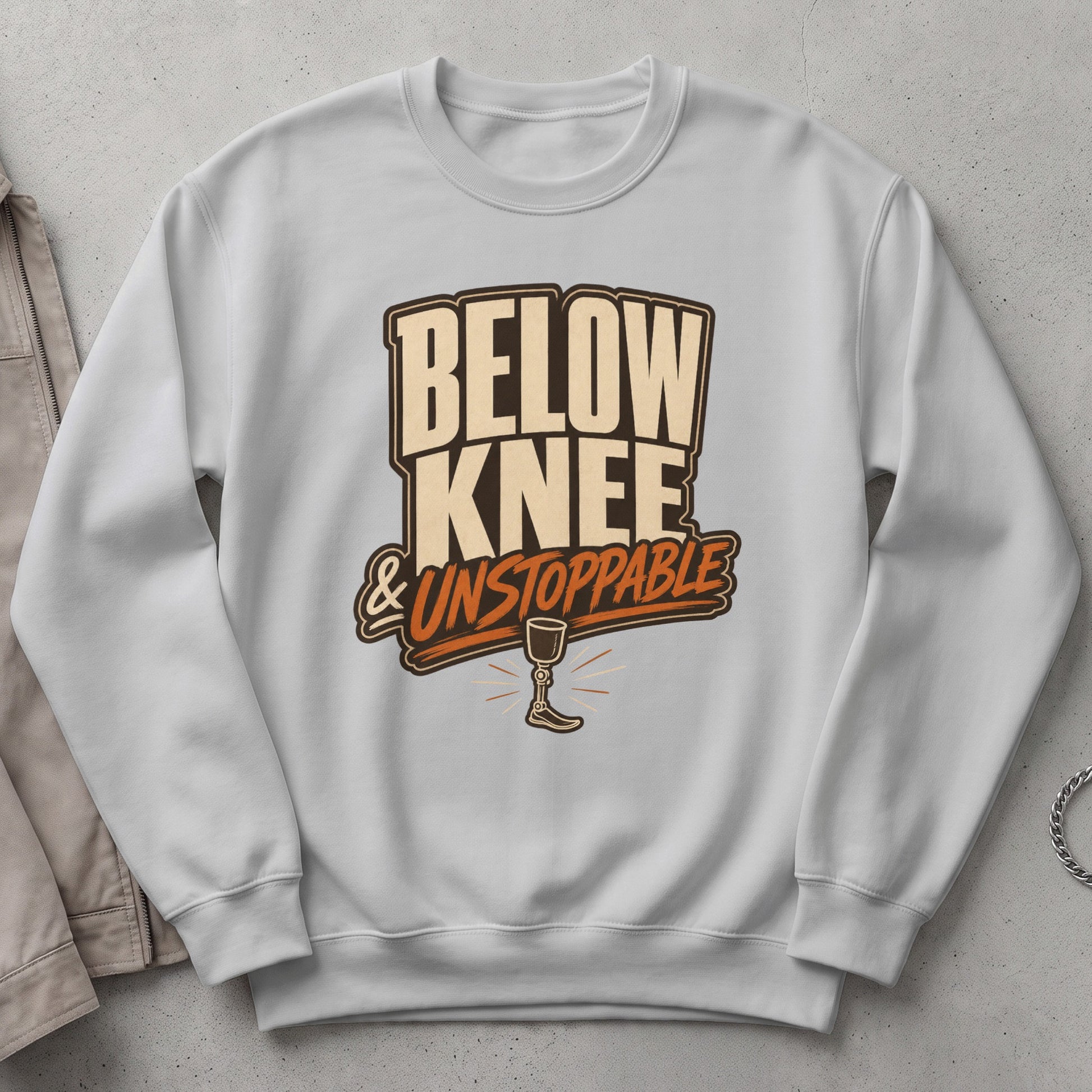White sweatshirt with text "Below Knee & Unstoppable" and prosthetic leg graphic.